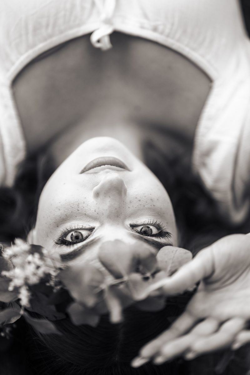 Czarnobiały portret kobiety w wianku, leżącej na drewnianym tle