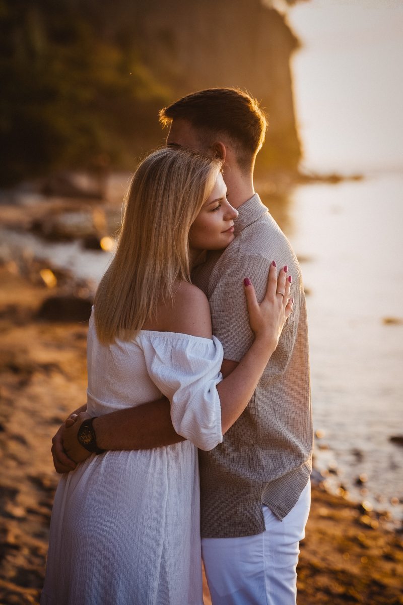 Wtulona para zakochanych na plaży, nad klifem, o wschodzie słońca.